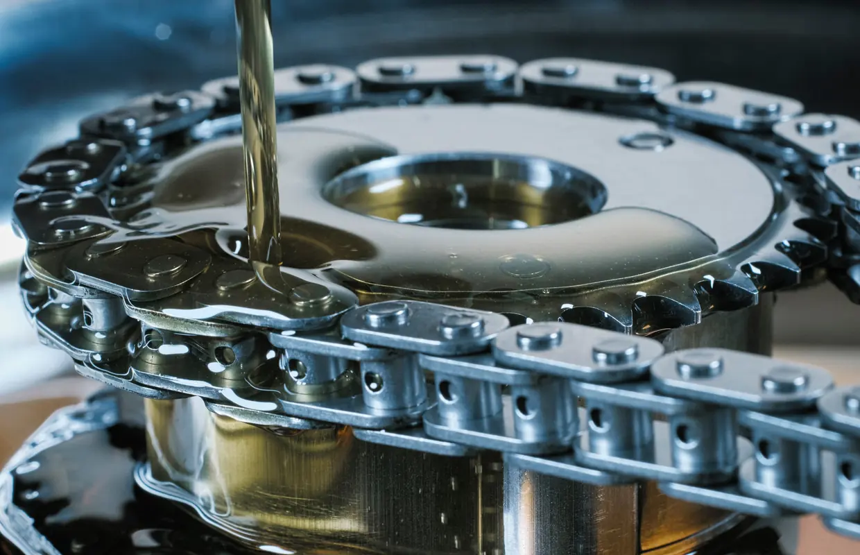 Engine oil being poured over a timing chain and sprocket