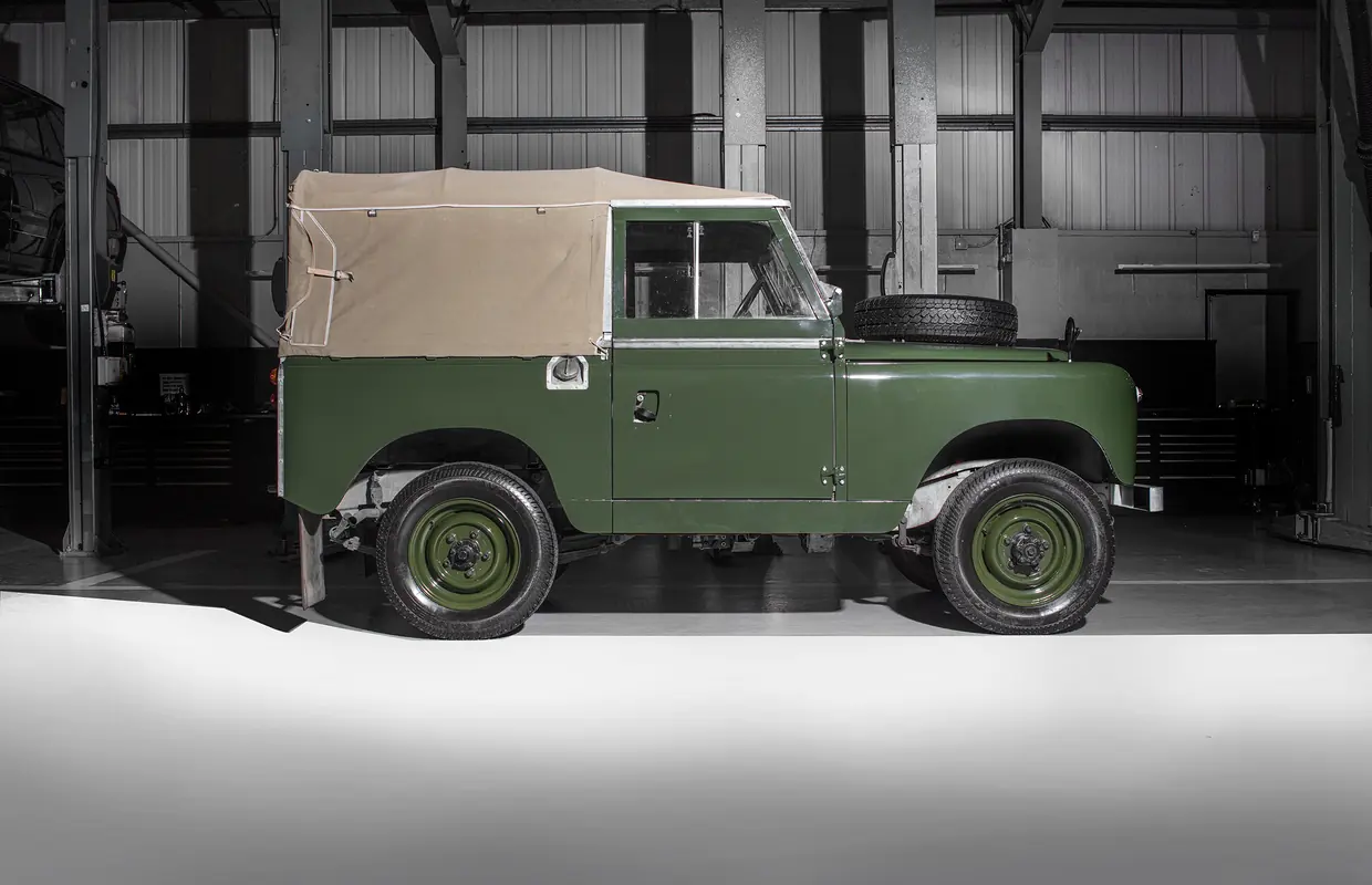 A restored green Series Land Rover with a canvas roof in the JLC workshop