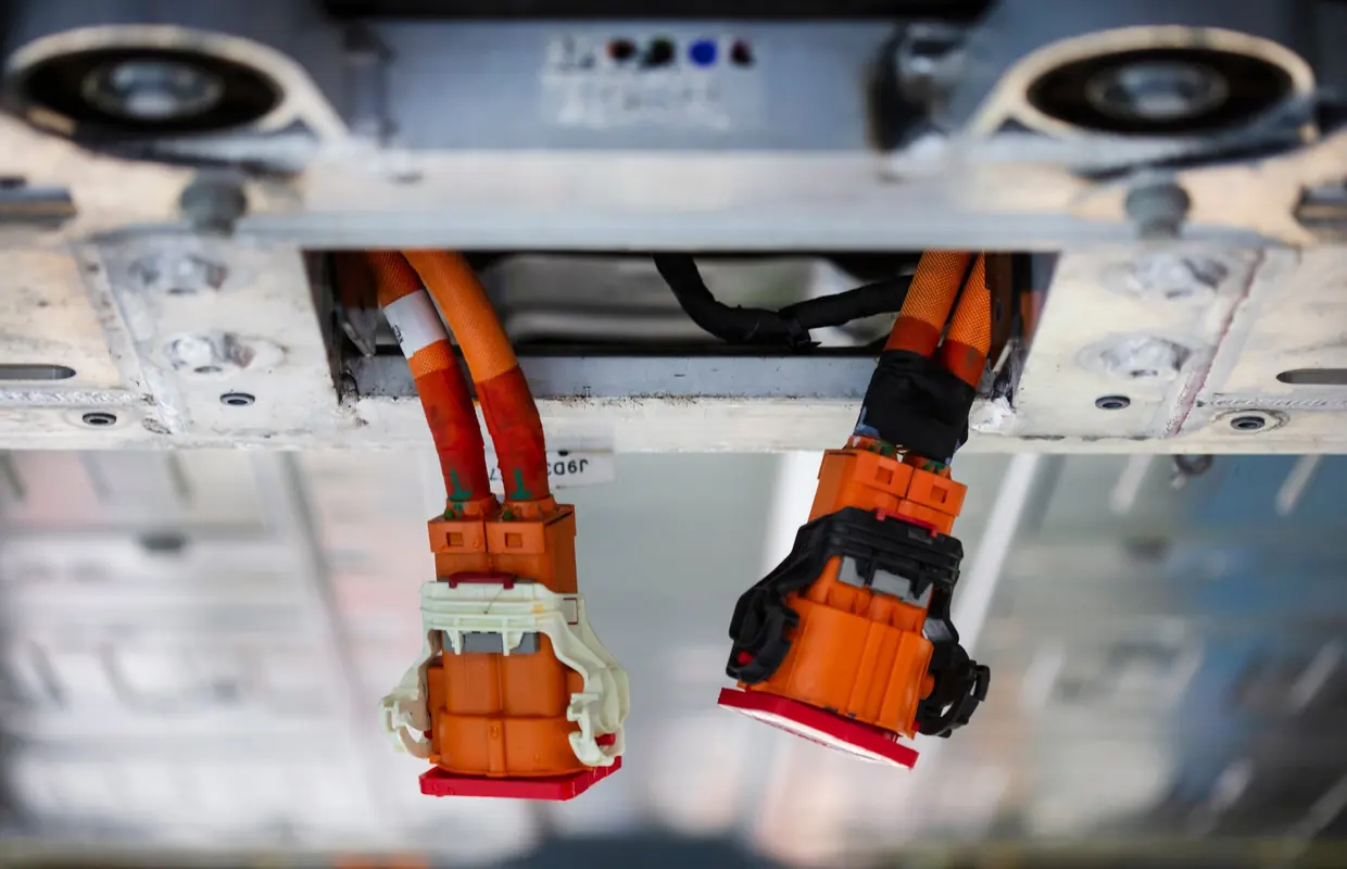 Orange high-voltage cables and connectors beneath a hybrid vehicle