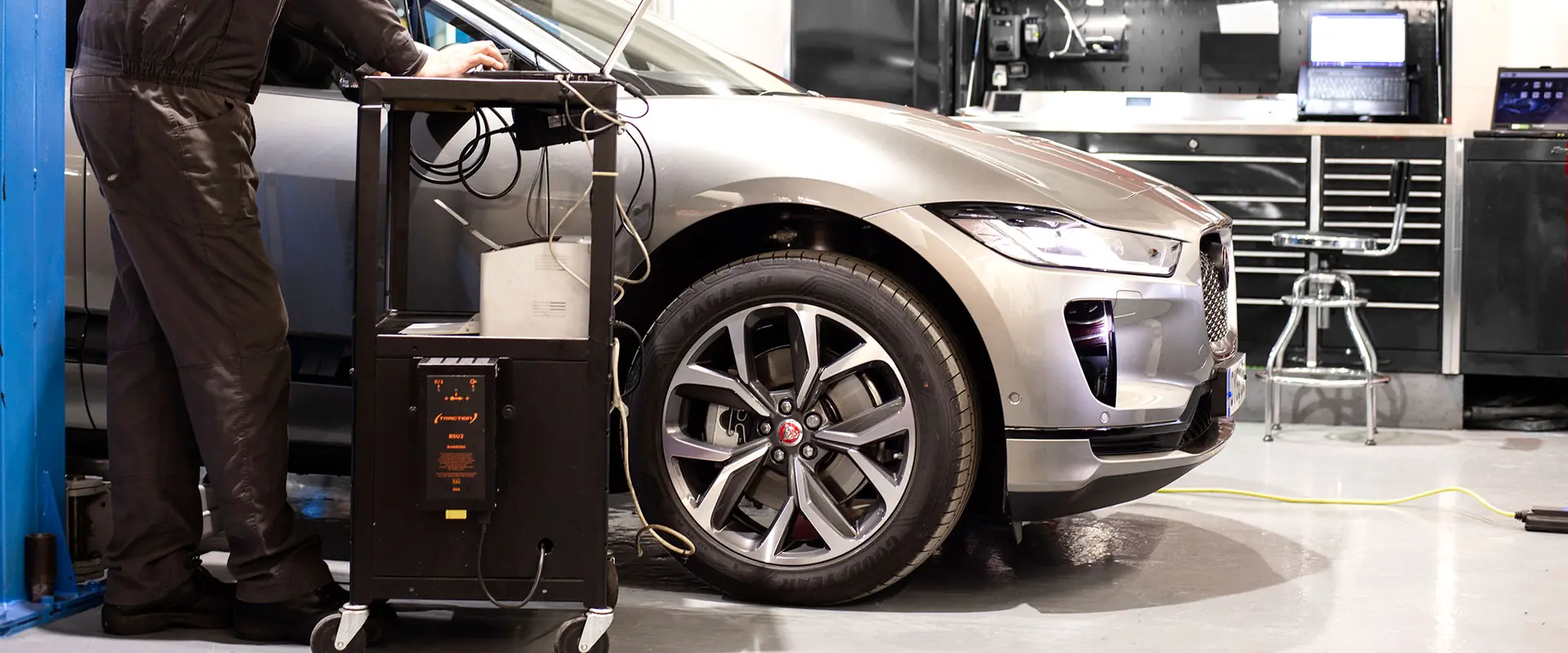 A JLC technician running diagnostics on a Jaguar I-PACE electric vehicle in the workshop