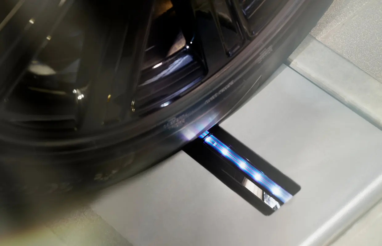 A Jaguar alloy wheel rolling over an in-floor tyre tread depth scanner