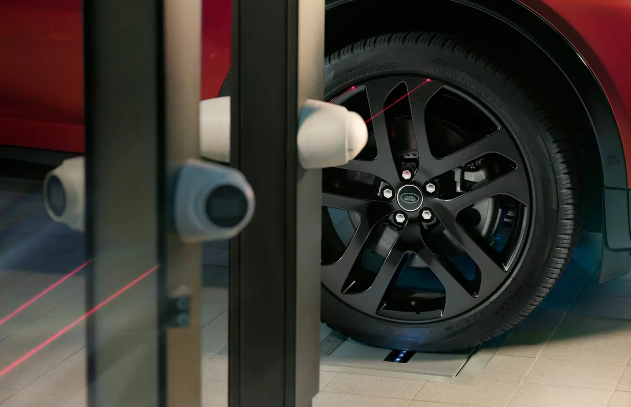 A Land Rover wheel being checked by laser alignment sensors in the workshop