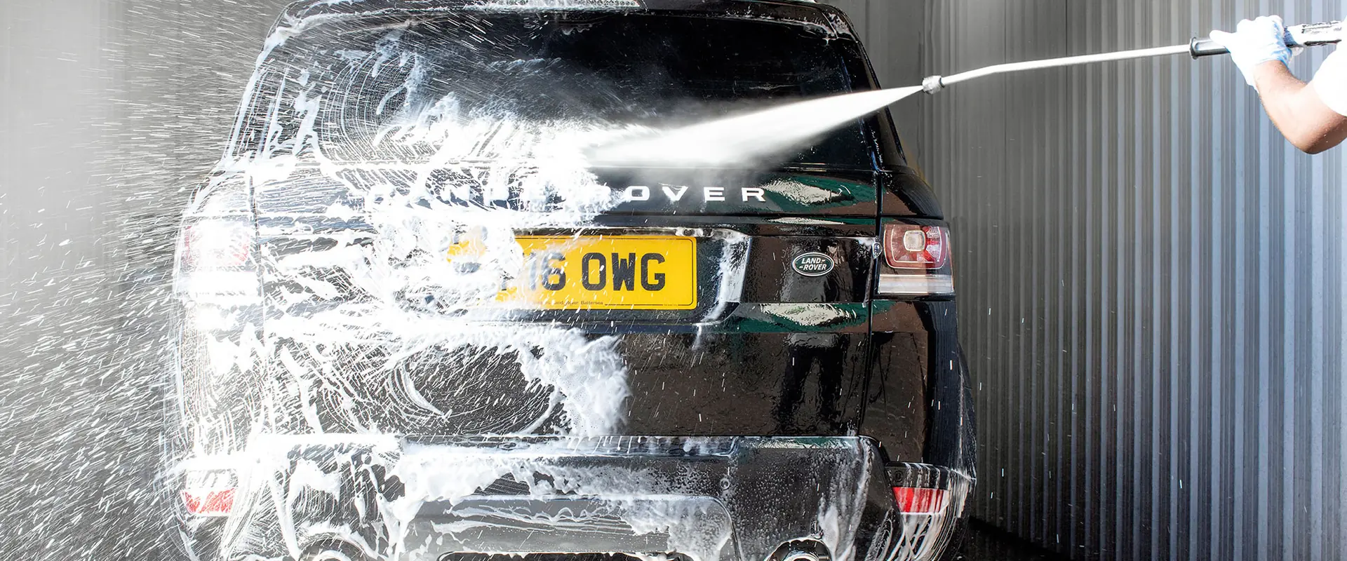 A black Range Rover Sport being pressure washed in the JLC valeting bay