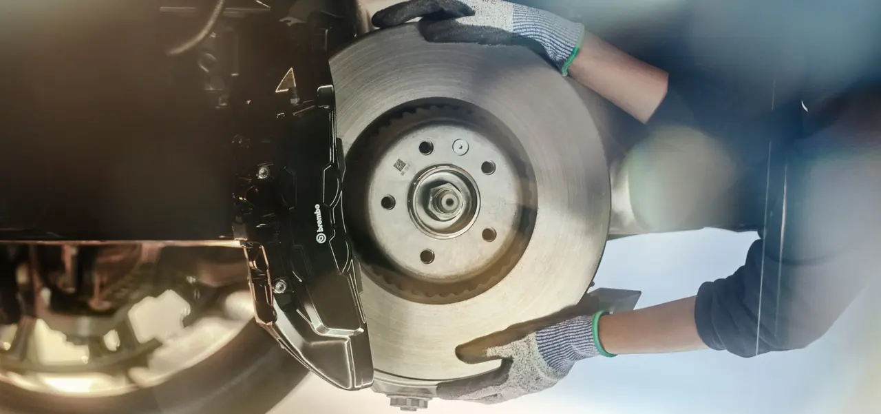 A JLC technician fitting a new brake disc and Brembo caliper during a service
